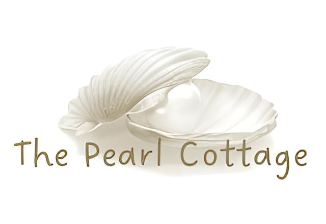 A white shell sitting next to a text that reads " the pearl cottage ".