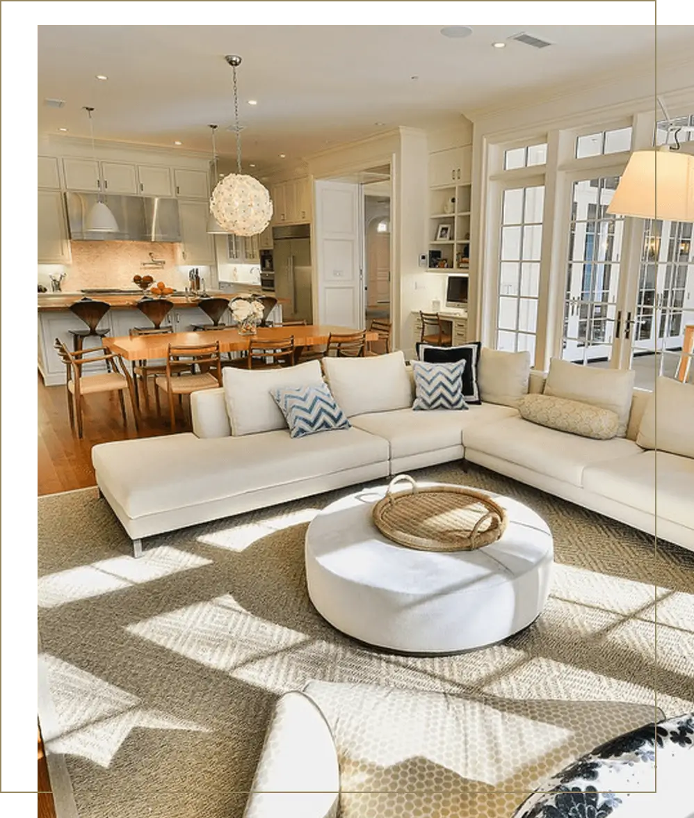 A living room with white furniture and a large open kitchen.