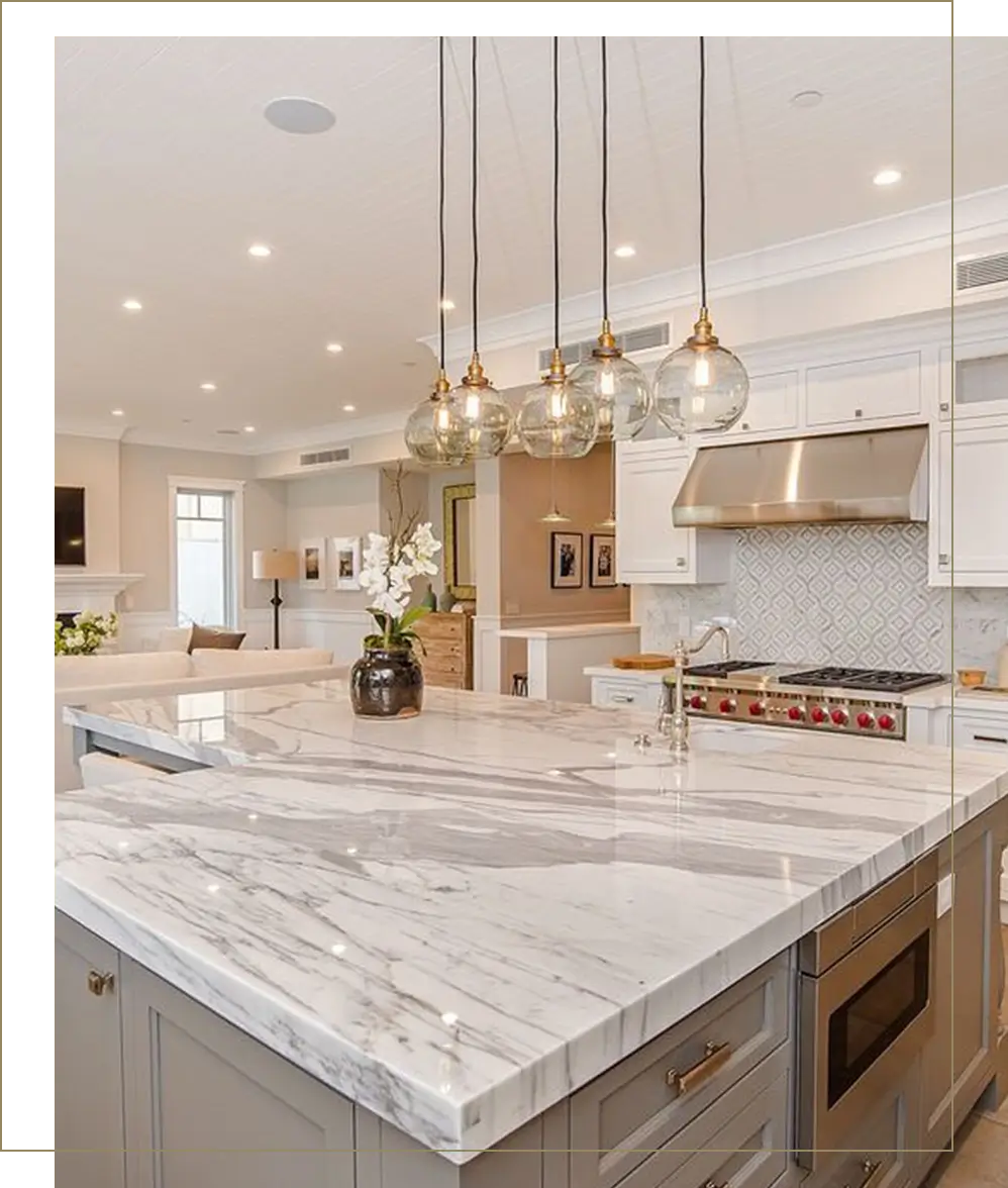 A kitchen with marble counter tops and hanging lights.